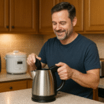A person using a modern electric kettle in a stylish American kitchen with appliances like a toaster, blender, and air fryer nearby.